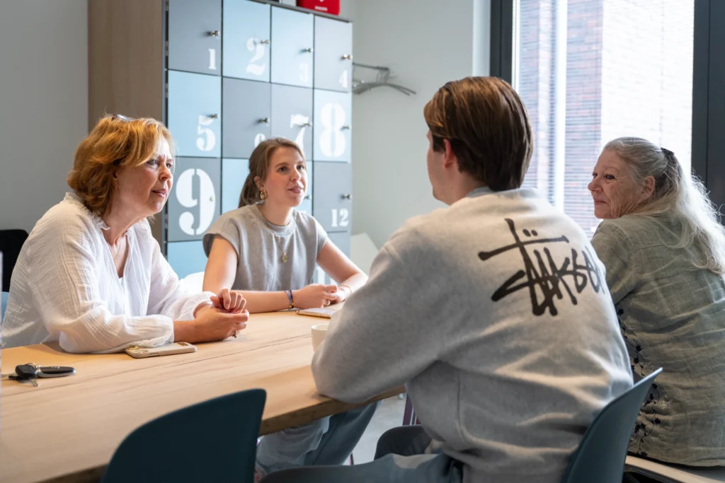 Groepsgesprek tijdens Loopbaancoaching, vier personen aan tafel.
