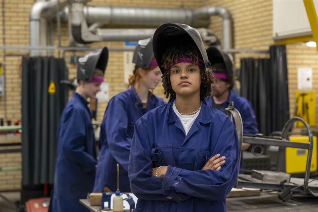 Studenten in blauwe overalls leren praktijkvaardigheden bij een erkend leerbedrijf